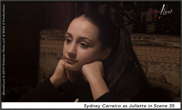 A young girl sits with her hands to her chin.